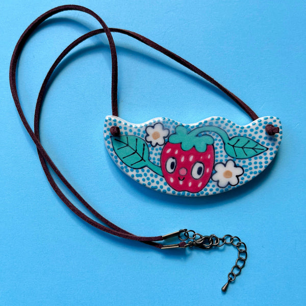 Necklace with a colorful pendant featuring a strawberry design on a blue background