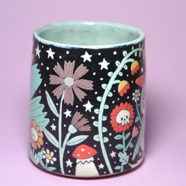 Ceramic mug with floral and mushroom design on a purple background