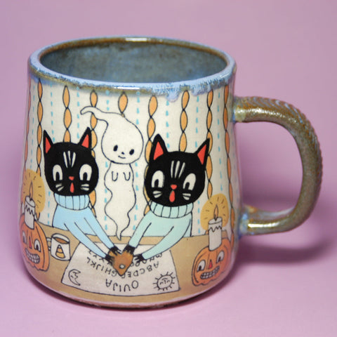 Ceramic mug with cat illustrations on a pink background