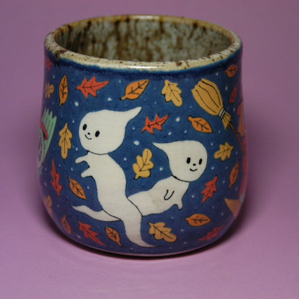 Ceramic cup with ghost and leaf design on a purple background