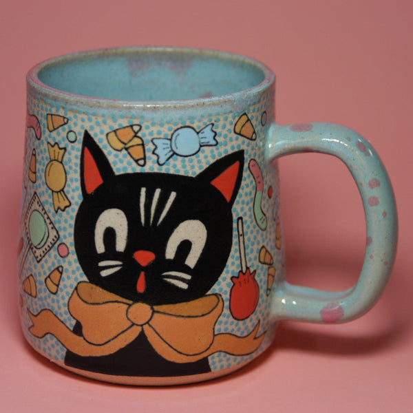 Ceramic mug with a black cat design on a pink background