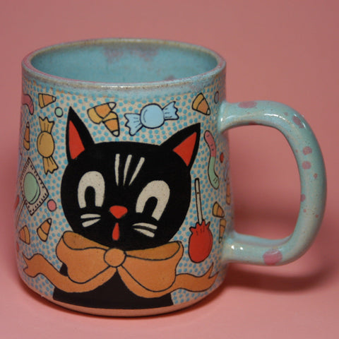Ceramic mug with a black cat design on a pink background