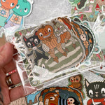 A collection of colorful stickers featuring various designs, held between fingers.