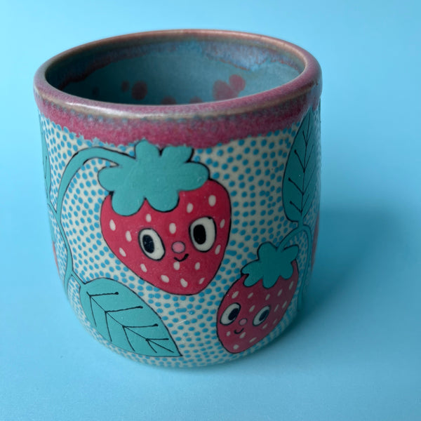 Ceramic cup with strawberry design on a blue background