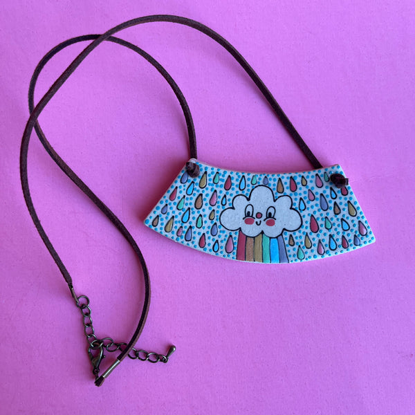 Necklace with a colorful pendant featuring a cloud and raindrops design on a pink background