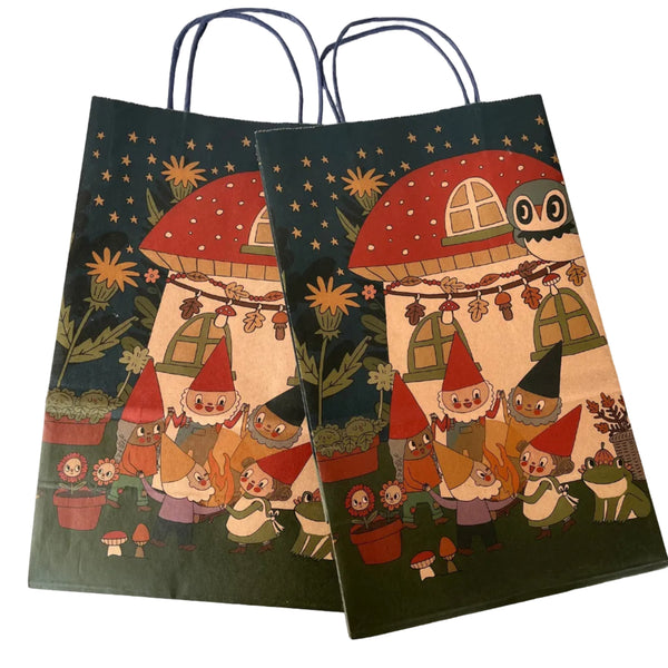 Two decorative gift bags with gnomes and mushroom design on a white surface.