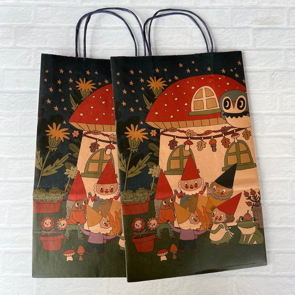 Two decorative bags with a cartoon gnome design of characters in red hats on a white brick wall background.