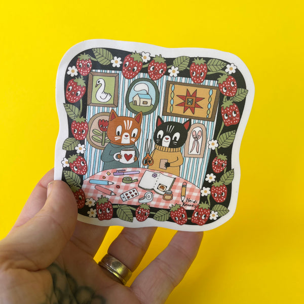Illustrated sticker of two cats at a table with a yellow background