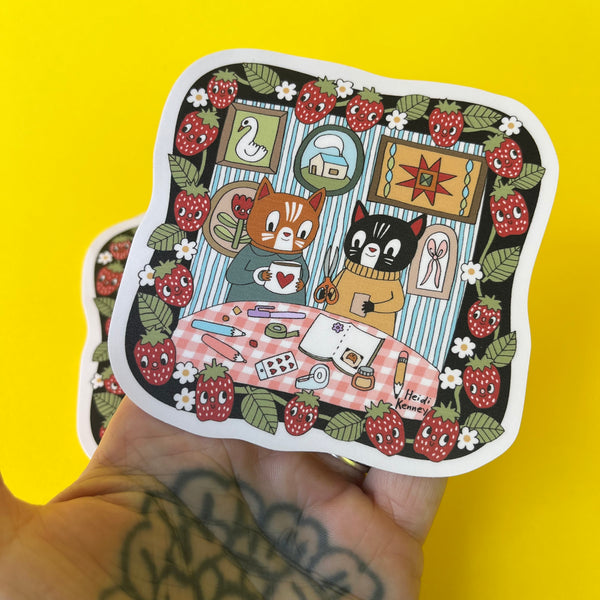 Sticker with cartoon cats at a table on a yellow background