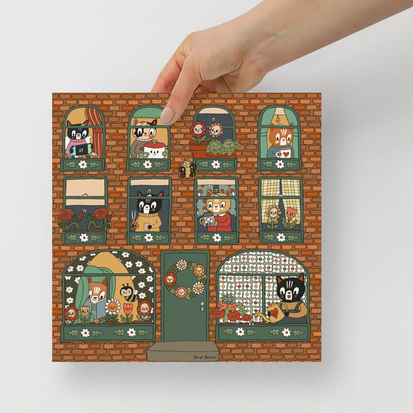 A print of a brick apartment building with cats doing different activities. 