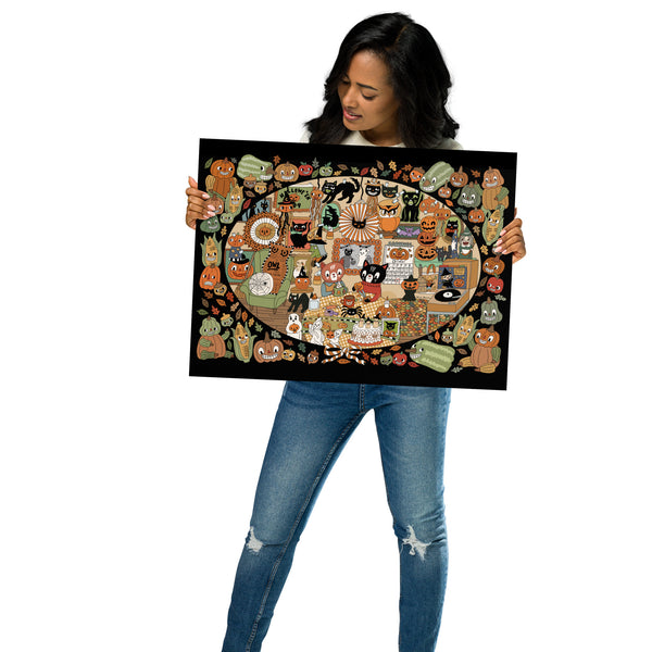 A woman holding a large, detailed art print featuring a whimsical autumn cat scene with pumpkins, leaves, and cozy indoor activities, set against a plain white background.
