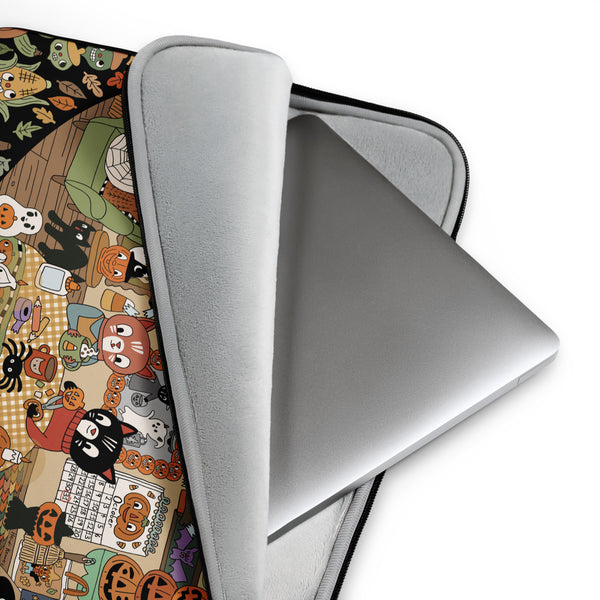 A silver laptop inside a light gray protective sleeve, shown on a white background with the sleeve's printed Halloween-themed fabric cover partially visible underneath.