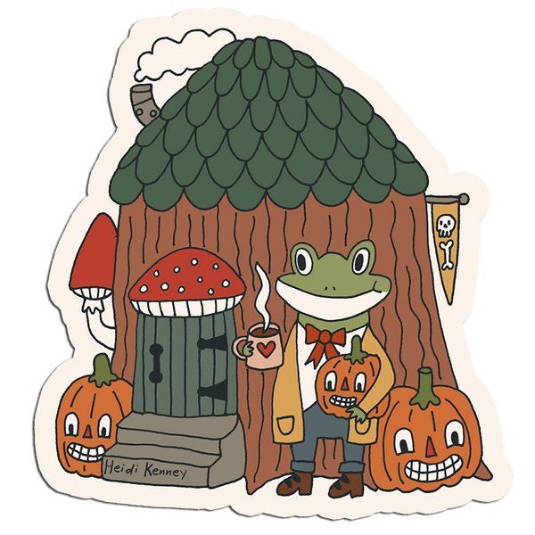 A die-cut sticker featuring a whimsical cartoon illustration of a green frog in a yellow coat standing in front of a mushroom house with a green scalloped roof, surrounded by jack-o'-lantern pumpkins and a red mushroom door. The artist signature 'Heidi Kenney' is visible in the lower left corner.