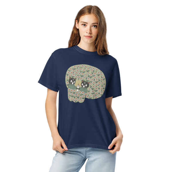 A woman modeling a navy blue short-sleeve t-shirt with a large graphic of a skull filled with a floral pattern and two cats inside, paired with light blue jeans against a plain white background.