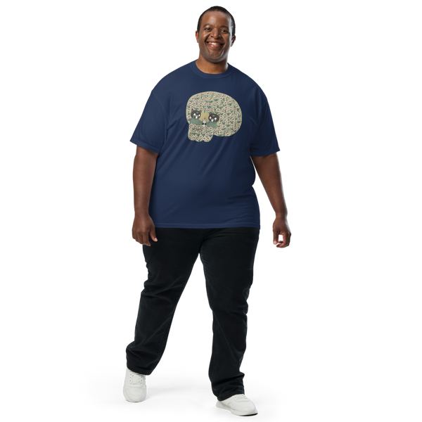 A smiling man wearing a navy blue t-shirt with a detailed skull graphic, paired with black pants and white sneakers, standing against a plain white background.